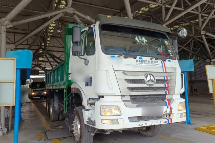 Tipper lorry in a PUSPAKOM inspection lane, licensed under a Surat Kelulusan