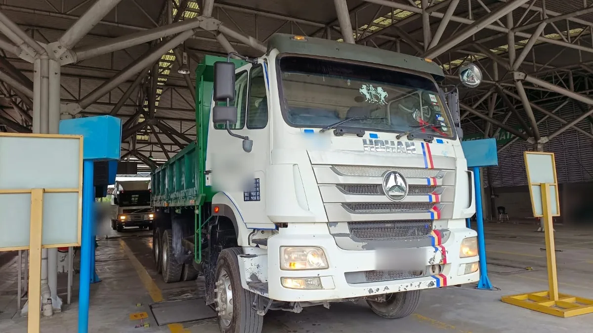 Tipper lorry in a PUSPAKOM inspection lane, licensed under a Surat Kelulusan
